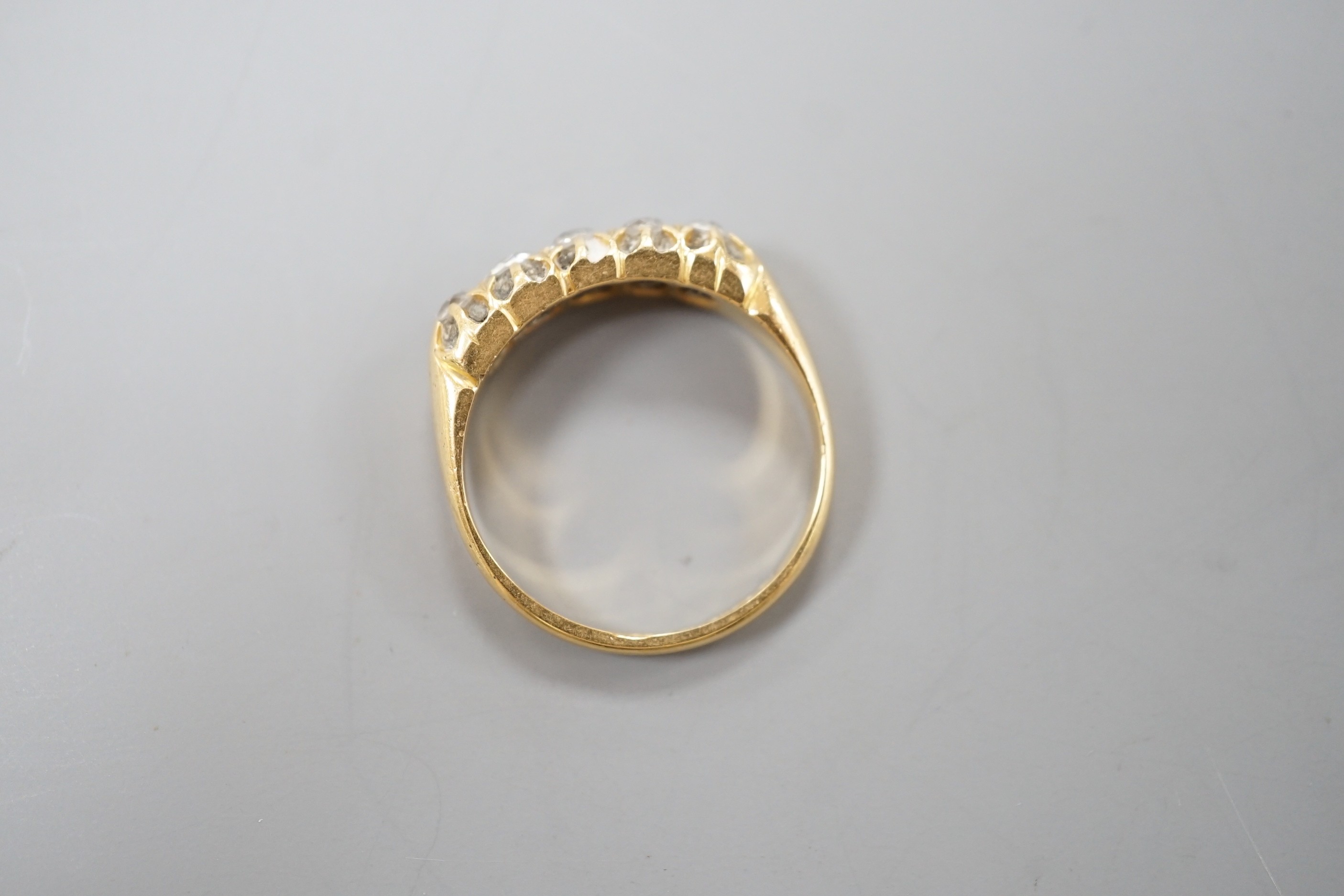 An early 20th century 18ct gold and graduated five stone diamond set half hoop ring, size N/O, gross weight 3.7 grams.